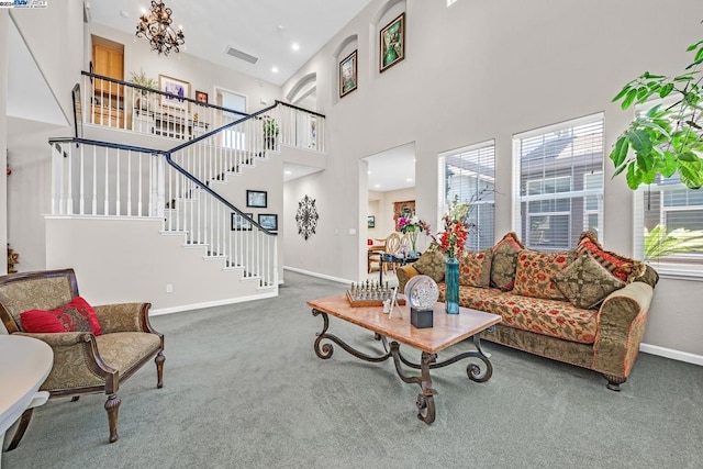 living room featuring a notable chandelier, a towering ceiling, and carpet floors