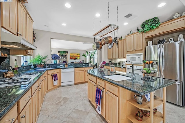 kitchen featuring kitchen peninsula, sink, stainless steel appliances, light brown cabinetry, and dark stone counters