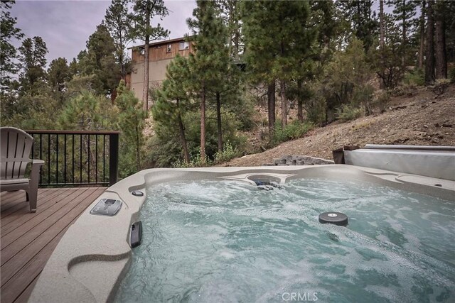 pool at dusk featuring a hot tub and a deck