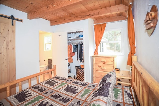 bedroom featuring beamed ceiling, a closet, a barn door, and wooden ceiling