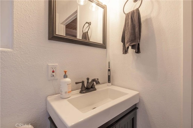 bathroom featuring a textured wall and vanity