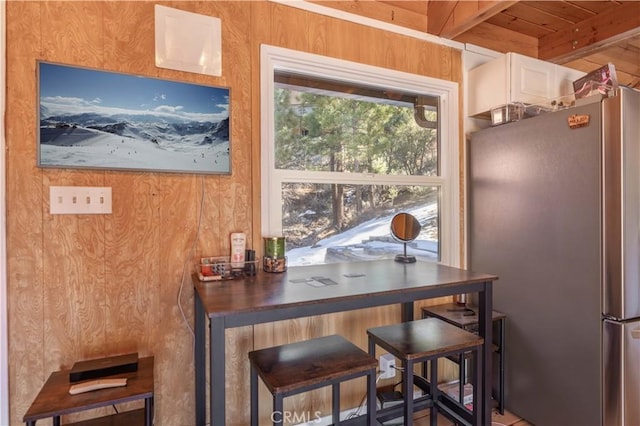 kitchen with freestanding refrigerator, white cabinetry, and beamed ceiling