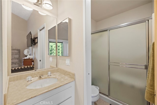 bathroom featuring a shower with door, vanity, and toilet