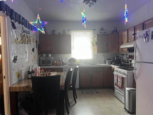 kitchen with sink, hanging light fixtures, and white appliances