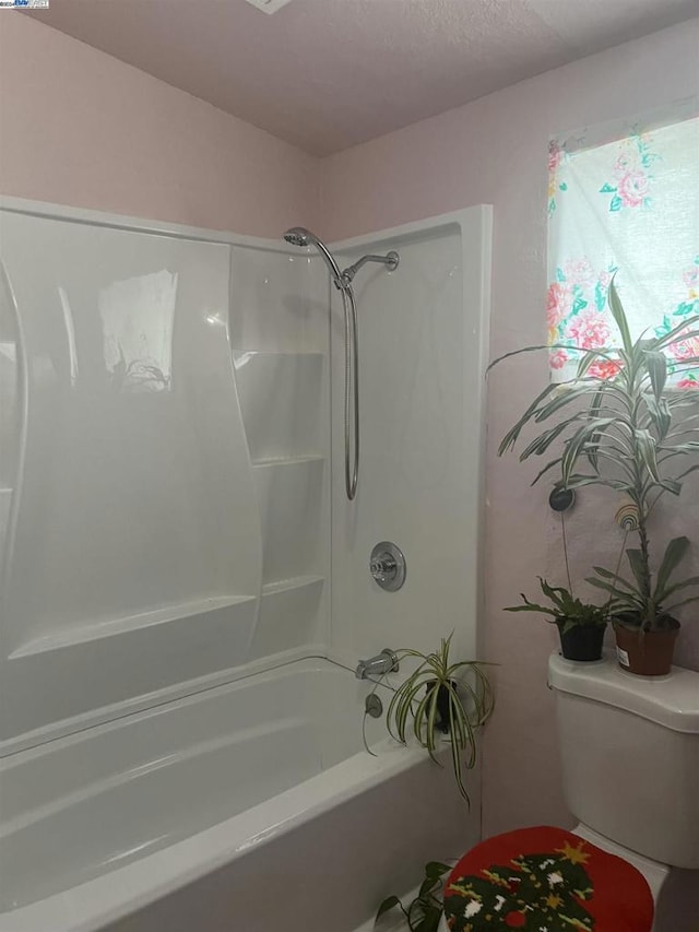 bathroom featuring shower / bathtub combination and toilet