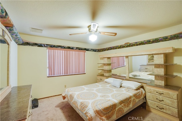 carpeted bedroom featuring a ceiling fan, baseboards, visible vents, and a textured ceiling