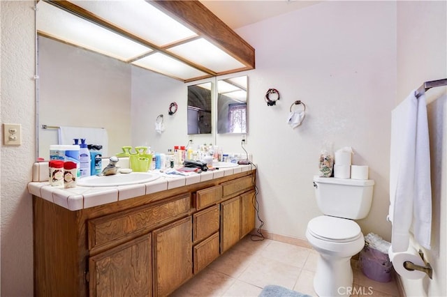 full bath featuring double vanity, a sink, tile patterned floors, and toilet