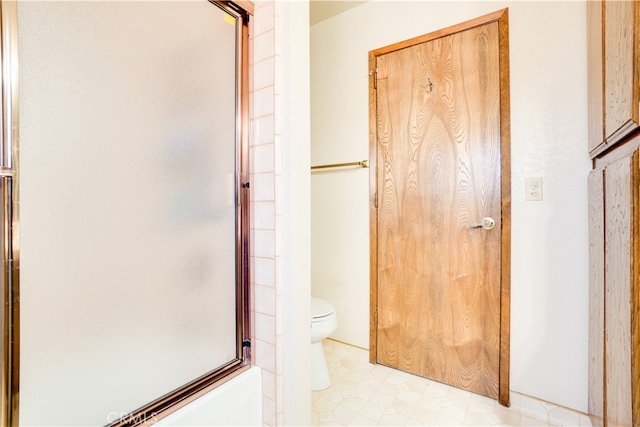 bathroom with tile patterned floors, toilet, and bath / shower combo with glass door