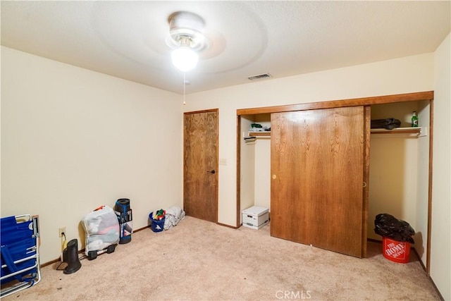 unfurnished bedroom featuring carpet floors, ceiling fan, visible vents, and a closet