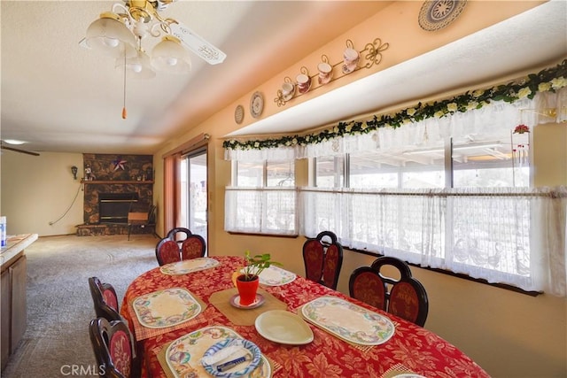 dining room featuring carpet floors and a stone fireplace