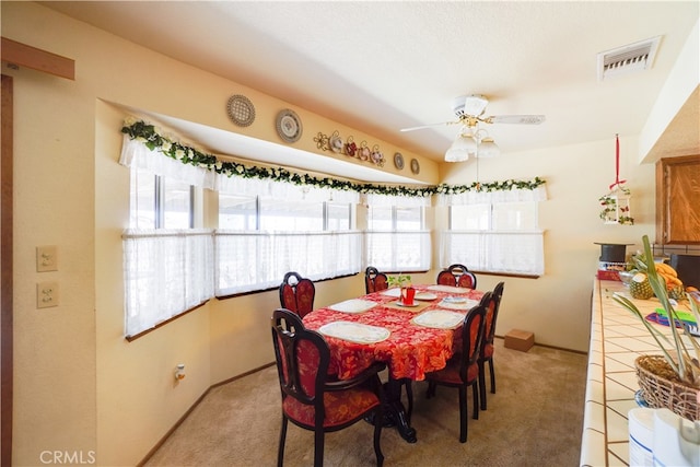 carpeted dining room with ceiling fan, visible vents, and baseboards