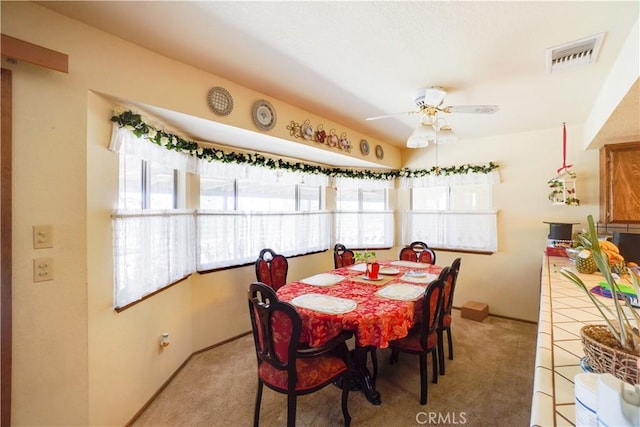 dining area featuring visible vents, a ceiling fan, baseboards, and light carpet