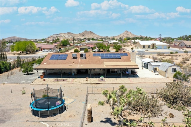 back of house featuring a trampoline, a mountain view, and a residential view