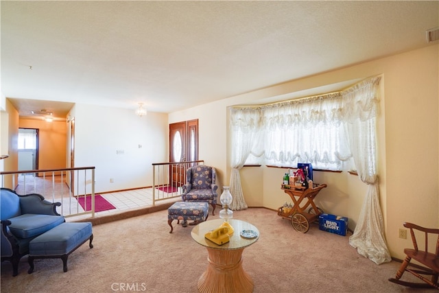 living area featuring baseboards, light colored carpet, visible vents, and an upstairs landing