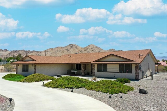 ranch-style house with fence, a mountain view, stucco siding, and stone siding