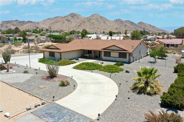 ranch-style house with a residential view, curved driveway, a mountain view, and fence