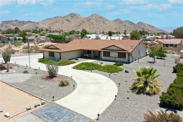 view of front of house featuring fence, curved driveway, a residential view, and a mountain view