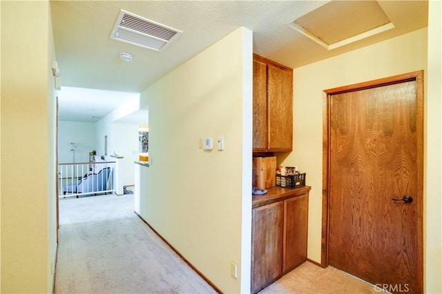 corridor featuring visible vents, light carpet, attic access, and an upstairs landing