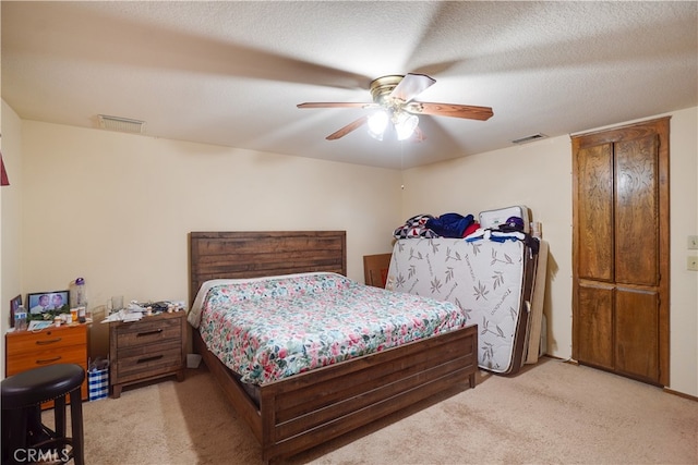 bedroom with a textured ceiling, visible vents, and light colored carpet