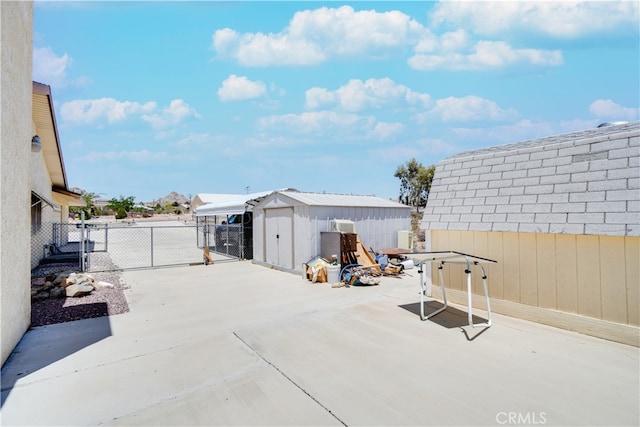 view of patio with an outbuilding, fence, and a storage unit