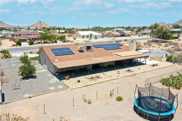 rear view of property featuring a trampoline, a residential view, and a mountain view