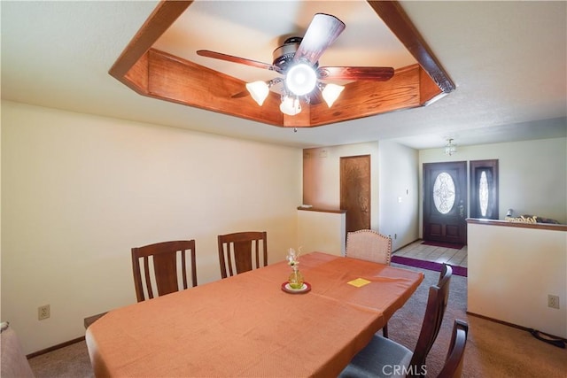 dining room featuring carpet flooring, a ceiling fan, baseboards, and a raised ceiling
