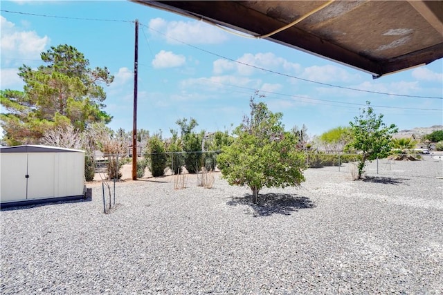 view of yard featuring fence, an outdoor structure, and a storage unit