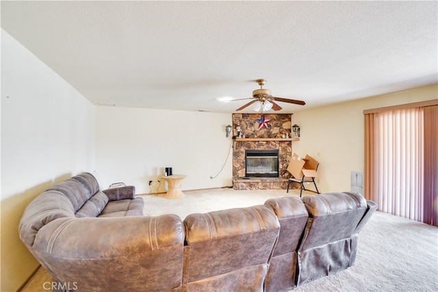 carpeted living area featuring a textured ceiling, a stone fireplace, and a ceiling fan