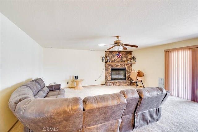 living area with a stone fireplace, carpet flooring, a textured ceiling, and a ceiling fan