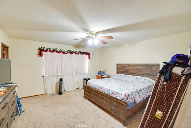 bedroom with a textured ceiling, light carpet, a ceiling fan, and baseboards