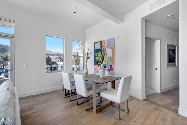 dining area with beam ceiling, light hardwood / wood-style floors, and a wealth of natural light