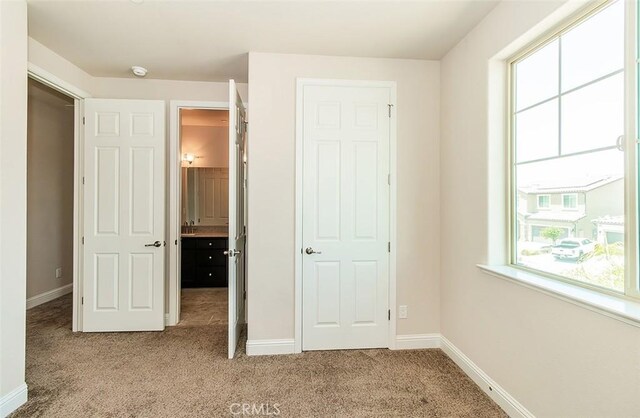 unfurnished bedroom featuring multiple windows and light carpet