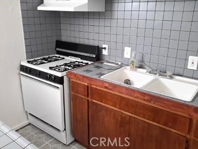 kitchen with range hood, sink, tasteful backsplash, and white gas range oven