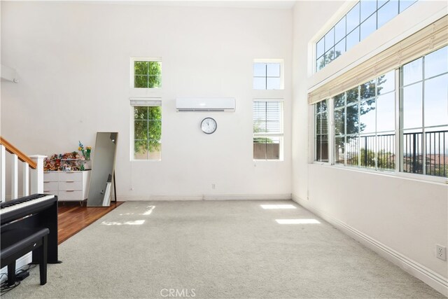 living room with carpet floors, a towering ceiling, an AC wall unit, and plenty of natural light