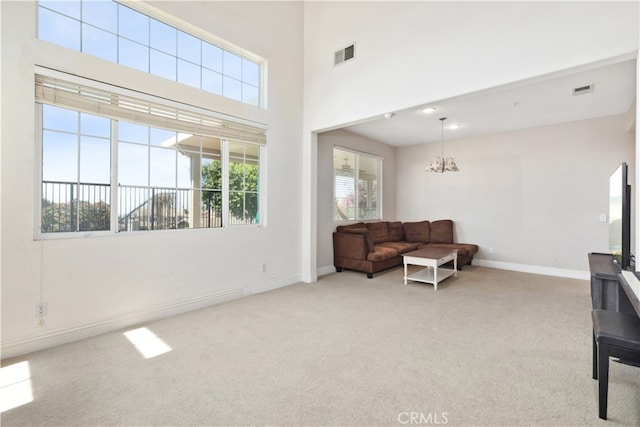 living area featuring light colored carpet, an inviting chandelier, and a high ceiling