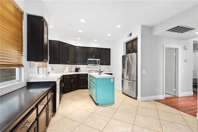 kitchen with an island with sink, stainless steel appliances, sink, and light tile patterned floors