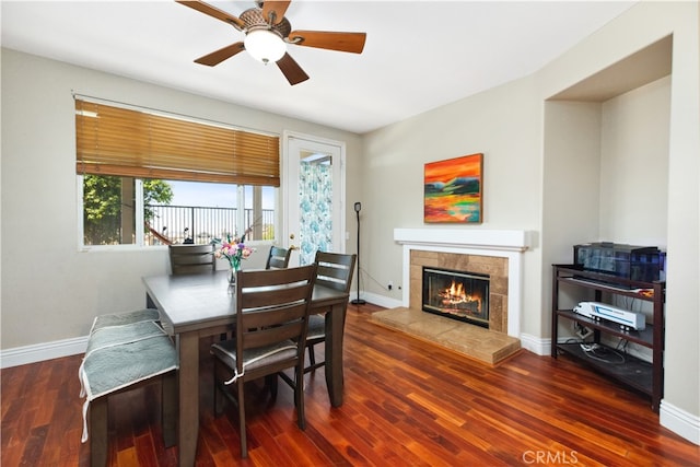 dining area featuring ceiling fan, a fireplace, and dark hardwood / wood-style floors