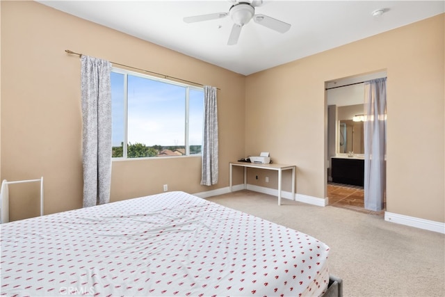 bedroom with ceiling fan, light carpet, and ensuite bathroom