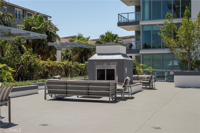 view of patio with an outdoor living space with a fireplace and a balcony