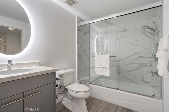 full bathroom featuring toilet, combined bath / shower with glass door, hardwood / wood-style flooring, and vanity