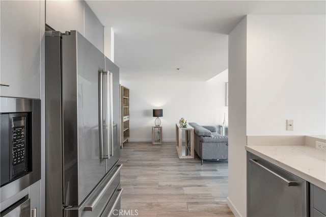 kitchen featuring light stone countertops, stainless steel appliances, and light wood-type flooring