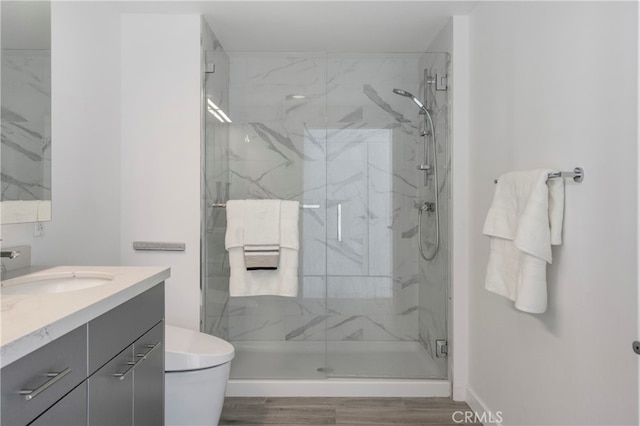 bathroom featuring toilet, an enclosed shower, hardwood / wood-style floors, and vanity