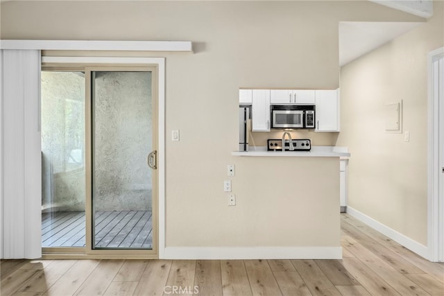 kitchen with white cabinets, stainless steel appliances, and light hardwood / wood-style floors