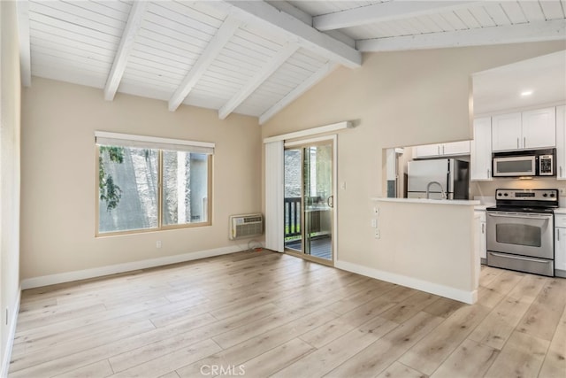 kitchen featuring appliances with stainless steel finishes, light hardwood / wood-style flooring, an AC wall unit, white cabinets, and vaulted ceiling with beams