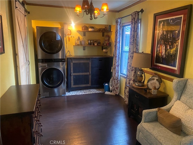 washroom featuring stacked washing maching and dryer, crown molding, a chandelier, and dark hardwood / wood-style floors