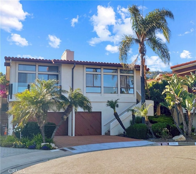 32701 Via Palacio, Rancho Palos Verdes, CA 90275 - mediterranean / spanish-style house with stucco siding, a chimney, an attached garage, decorative driveway, and a tiled roof