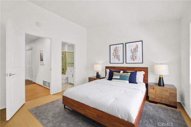 bedroom with hardwood / wood-style flooring and ensuite bath