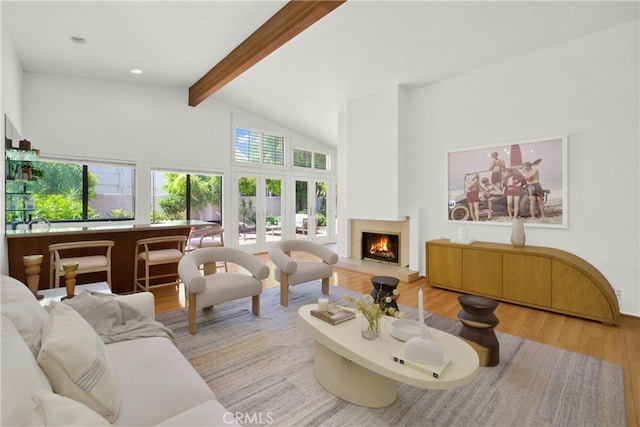 living room featuring beamed ceiling, high vaulted ceiling, light hardwood / wood-style flooring, and a healthy amount of sunlight