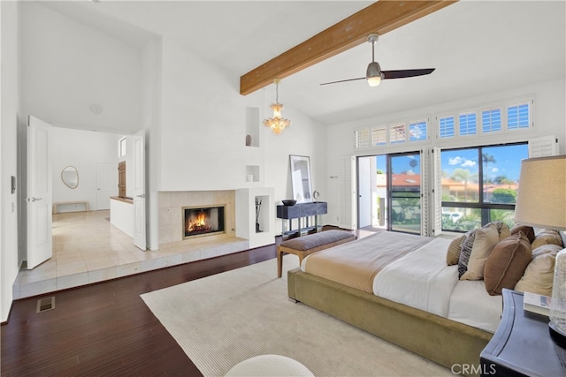 bedroom with beam ceiling, a tile fireplace, ceiling fan, high vaulted ceiling, and light wood-type flooring