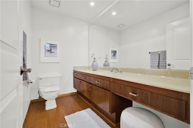 bathroom with wood-type flooring, vanity, and toilet